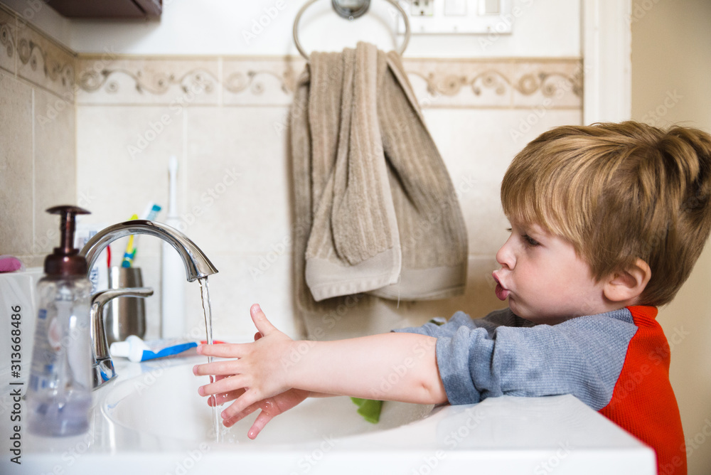 A little boy washes his hands in the bathroom sink. A little boy washes his hands in the bathroom sink.