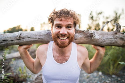 portrait of man balancing log on shoulders during an outdoor workout. photo