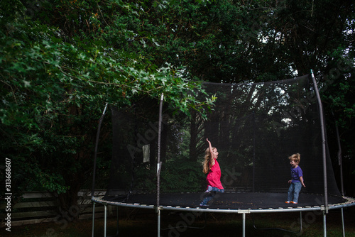 A girl and boy jump on an outdoor trampoline. photo