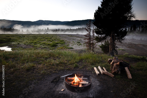 A morning campfire and a woman having breakfast camping on the Upper Snake River in the John D. Rockefeller Jr. Memorial Parkway photo