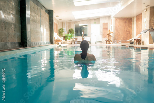 Rear view of a woman relaxing in spa pool photo