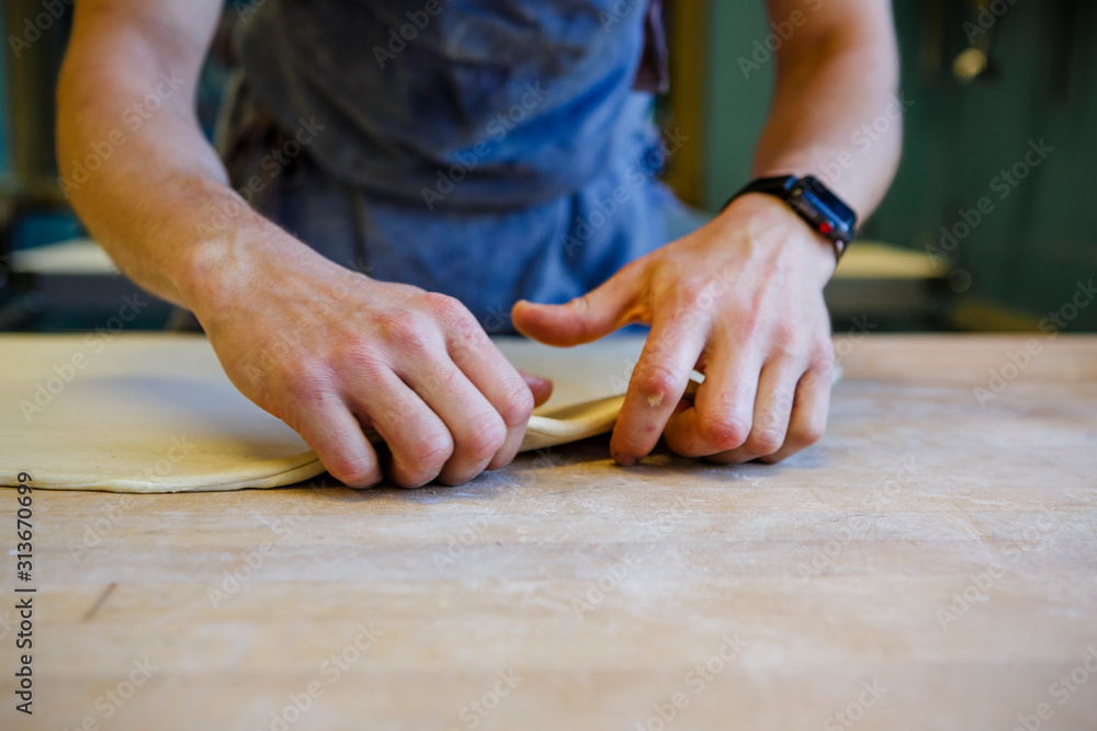 A baker working in a commercial kitchen folding pastry dough A baker working in a commercial kitchen folding pastry dough