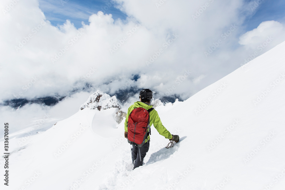 A young man descends from the summit of Mt. Hood on a cloudy day. A young man descends from the summit of Mt. Hood on a cloudy day.