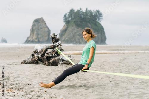 Girl is sitting on slackline at LaPush beach in Olympic National Park photo