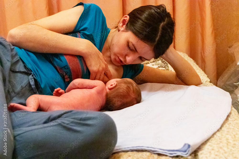 Young Caucasian mother lies with her newborn Young Caucasian mother lies with her newborn
