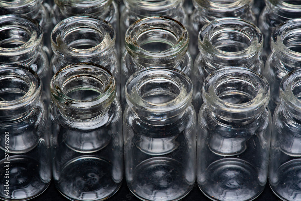 standing group of tiny glass bottles on a black surface, studio photo shoot 