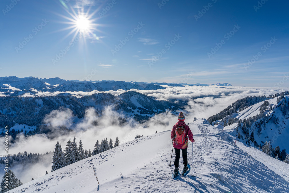 nice senior woman snowshoeing on the Nagelfluh chain above a sea of fog over Bregenz Wald mountains, Hochgrat, Steibis,Bavarian alps, 