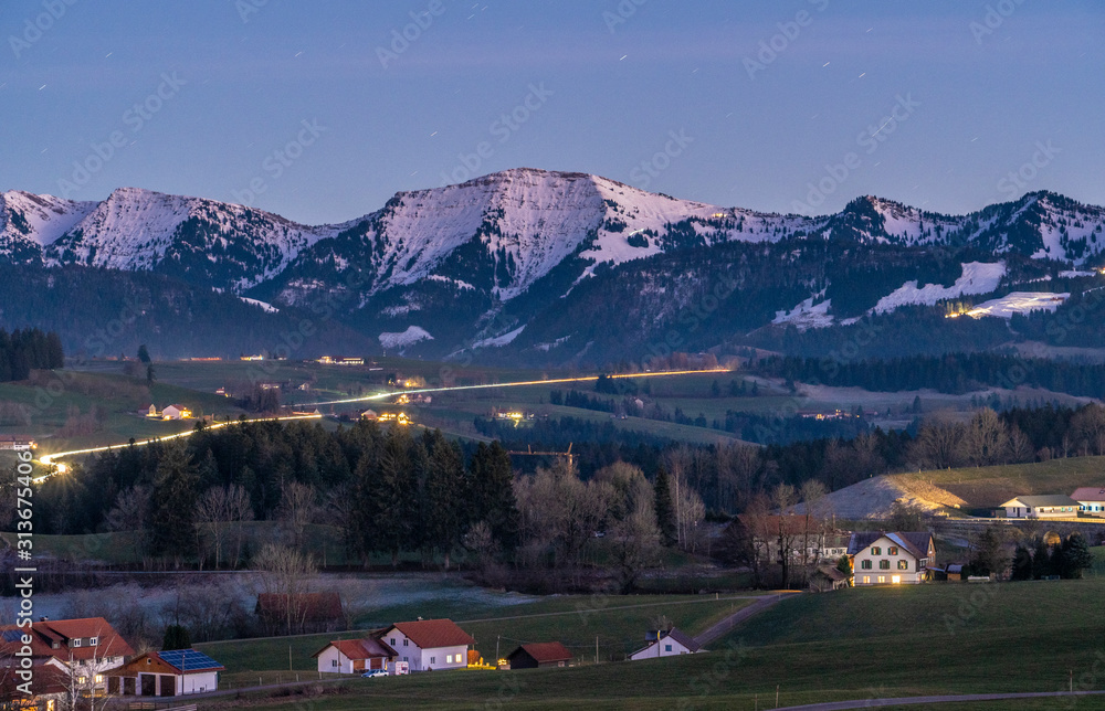 Fototapeta premium Hochgrat summit in the Nagelfluh chain with village of Oberreute in the foreground at Dawn, Allgau Alps near Oberstaufen, Bavaria, Germany, landscape photography
