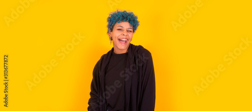 young african american girl or woman with blue hair isolated on yellow background