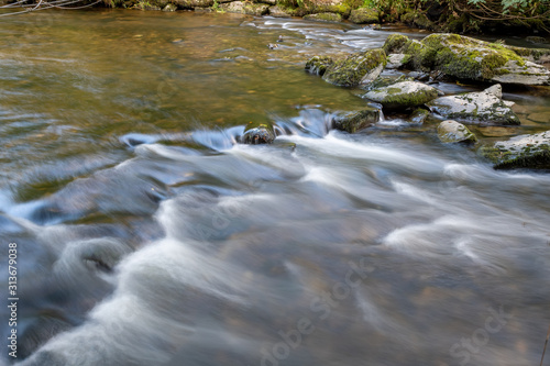 Long exposure of the river Barle flowing through the woods at Tarr Steps in Exmoor national park. photo