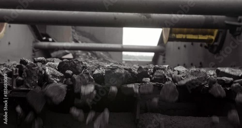 Conveyor belt with coal shooting in slow motion. Close-up there is coal on belt conveyor. Conveyor belt coal. Machine for loading mining in coal obage factory
