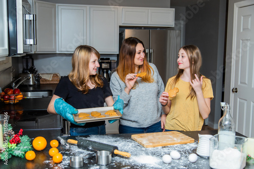 white Caucasian family, mother and teenager children cooking and decorating cookies on Christmas and New year Holiday on kitchen.