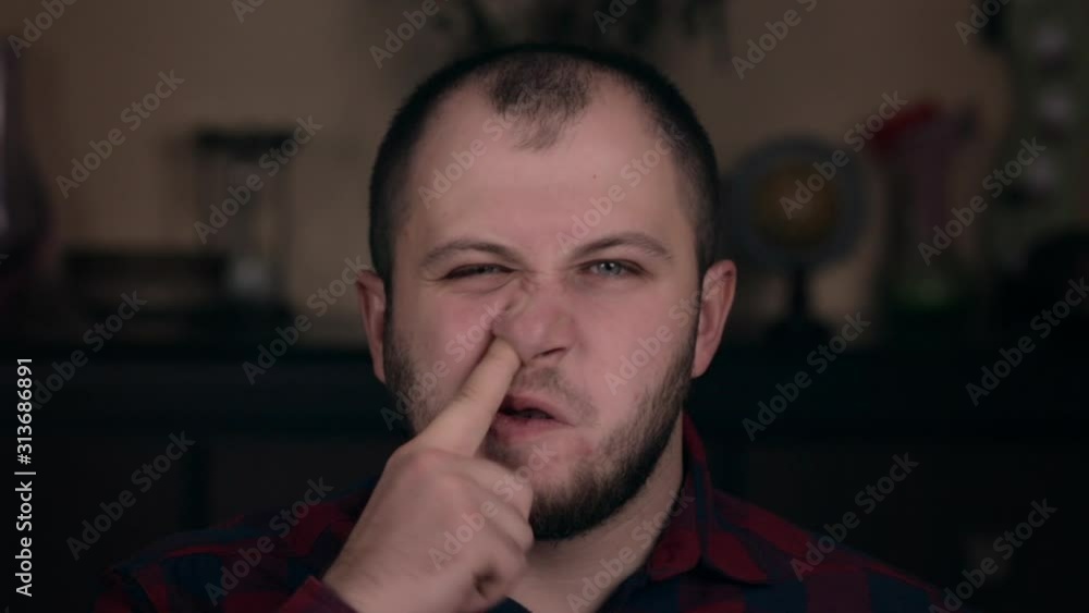 A young guy of European appearance in a plaid shirt is closeup picking his nose. The concept of emotions A young guy of European appearance in a plaid shirt is closeup picking his nose. The concept of emotions