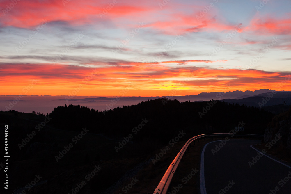 Dramatic red sky with reflections on guard rail road Dramatic red sky with reflections on guard rail road