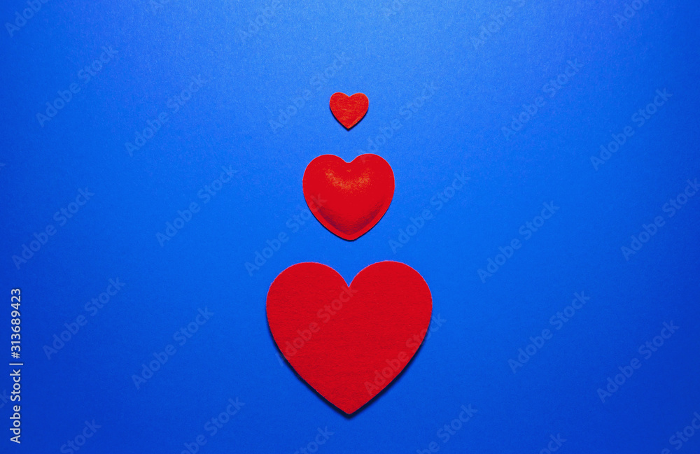 Decorative felt hearts on blue background. Abstract backdrop with copy space. Love and romance theme. Decorative felt hearts on blue background. Abstract backdrop with copy space. Love and romance theme.