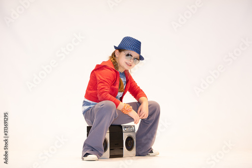 little girl with a boombox, children's model in a hat and glasses, hip hop girl on a white background,