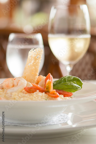 Risotto with shrimp, tomato and basil and glass in the back