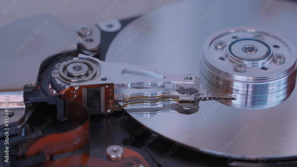 Spinning Hard disk drive platter. Disassembled hard drive from the computer with mirror effect. HDD) .Detail of writing/reading head on actuator arm and axis, spindle and platters. Spinning Hard disk drive platter. Disassembled hard drive from the computer with mirror effect. HDD) .Detail of writing/reading head on actuator arm and axis, spindle and platters.