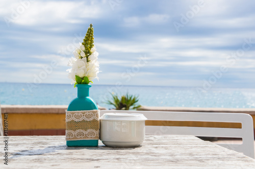 Vase with the flowers on the table in summer cafe. photo