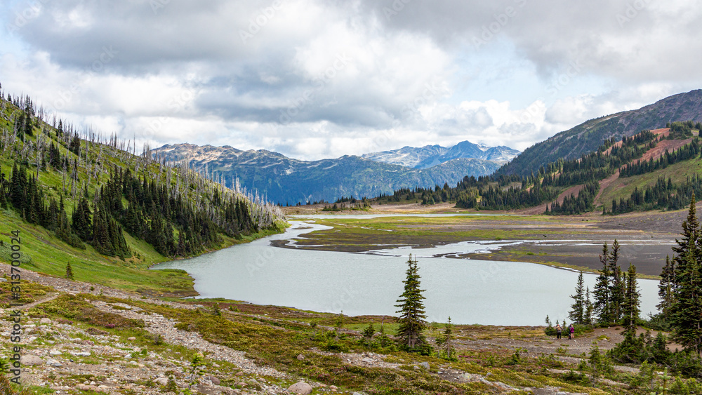 Snowy mountains with a lake at the bottom and cloudy sky