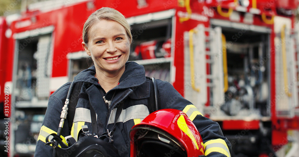 Close up photo of Female firefighter in protective suit with oxygen mask and helmet in her hands