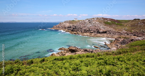 Brittany coastline with a rocky ocean bay and fern plants near Millier lighthouse in Beuzec-Cap-Sizun, France