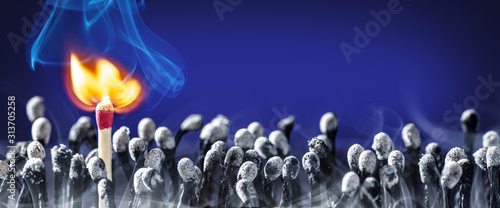 Φωτογραφία New Match Bursting Into Flames Standing In Group Of Old Burnt Matchsticks - New