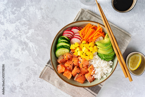 Top view of poke bowl with vegetables, rice and salmon