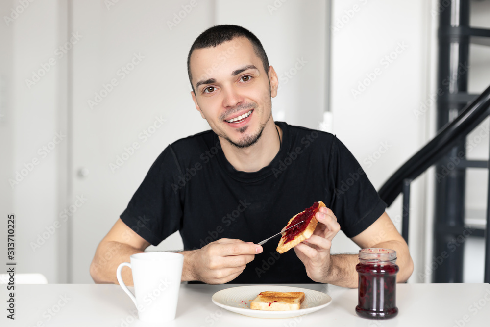 The guy has breakfast with toast with jam. The guy has breakfast with toast with jam.