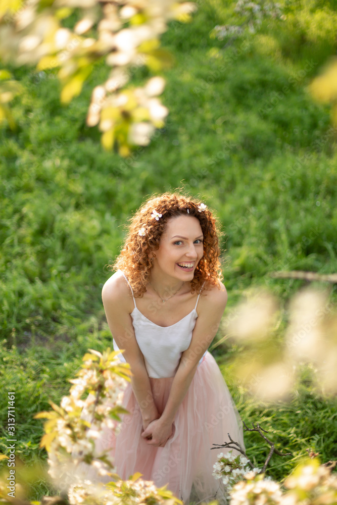 Young attractive girl walks in spring green park enjoying flowering nature Young attractive girl walks in spring green park enjoying flowering nature