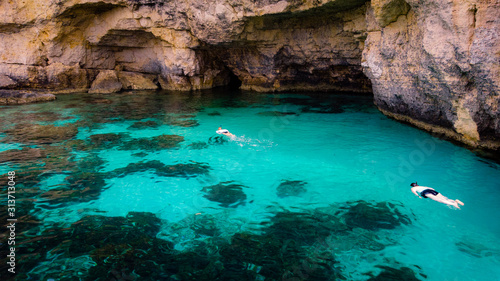 Swimmers snorkel in the warm clear mediterranean waters of the blue lagoon near Comino in Malta.
