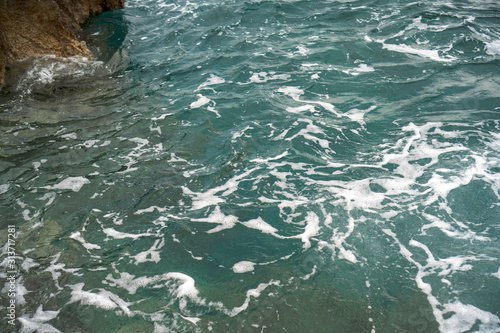 Raging blue water in a backwater with stones and white foam.