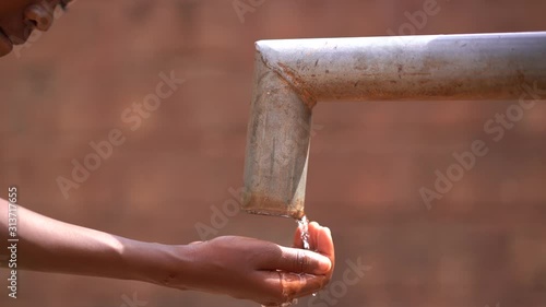 Close Up of a Girl's Hand Reaching Out For Water At the Village Pump Station