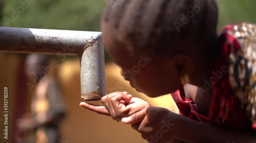 African Girl Counting Drops At A Drying Out Water Pump Station