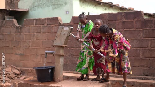 Three Little African Girls Pumping Water At The Community Well