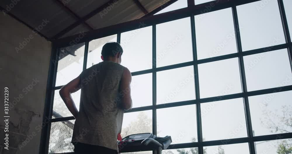 Man running on treadmill in home fitness gym. Man running on treadmill in home fitness gym.