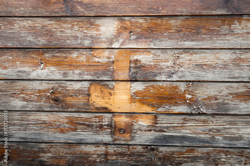 The wall of old wooden boards, varnished with traces of the Orthodox cross.