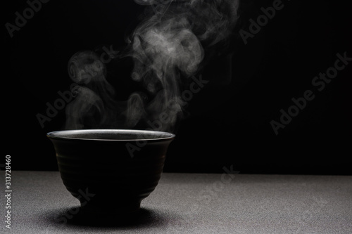 Soup hot in black bowl on wooden table,food steam and copy space ,selective focus.Fresh foods concept