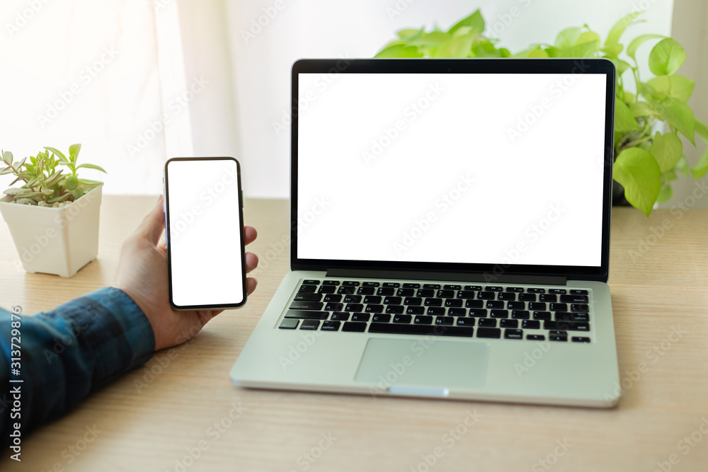Fototapeta premium mockup image blank screen computer,cell phone with white background for advertising text,hand man using laptop texting mobile contact business search information on desk in office.marketing,design