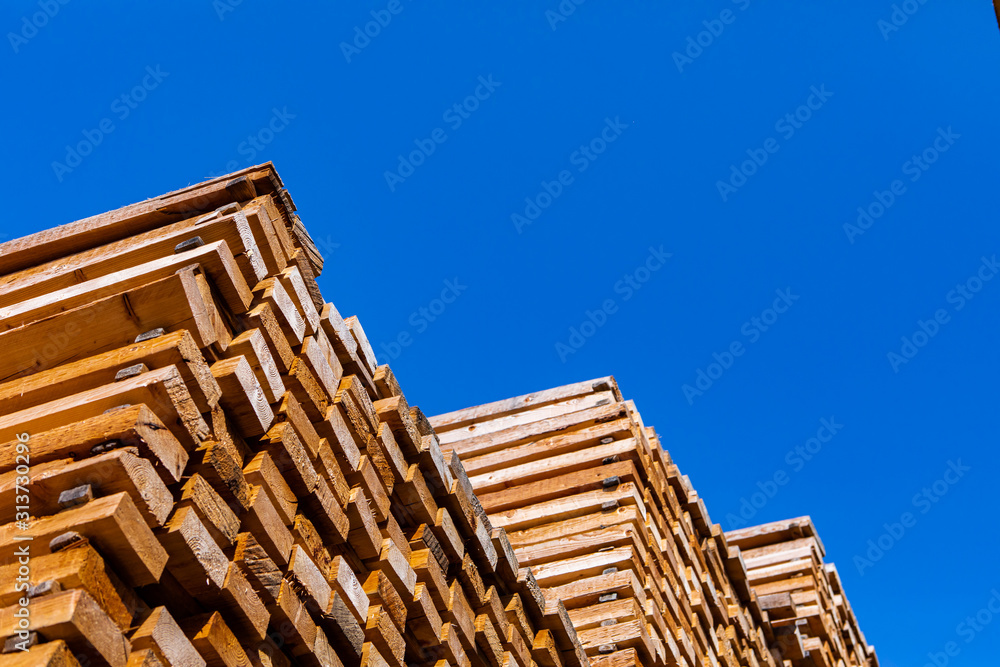 A low angle shot of a large pile of lumber boards stored in a sawmill yard. Woodworking and timber manufacture and supply industry, with copy space