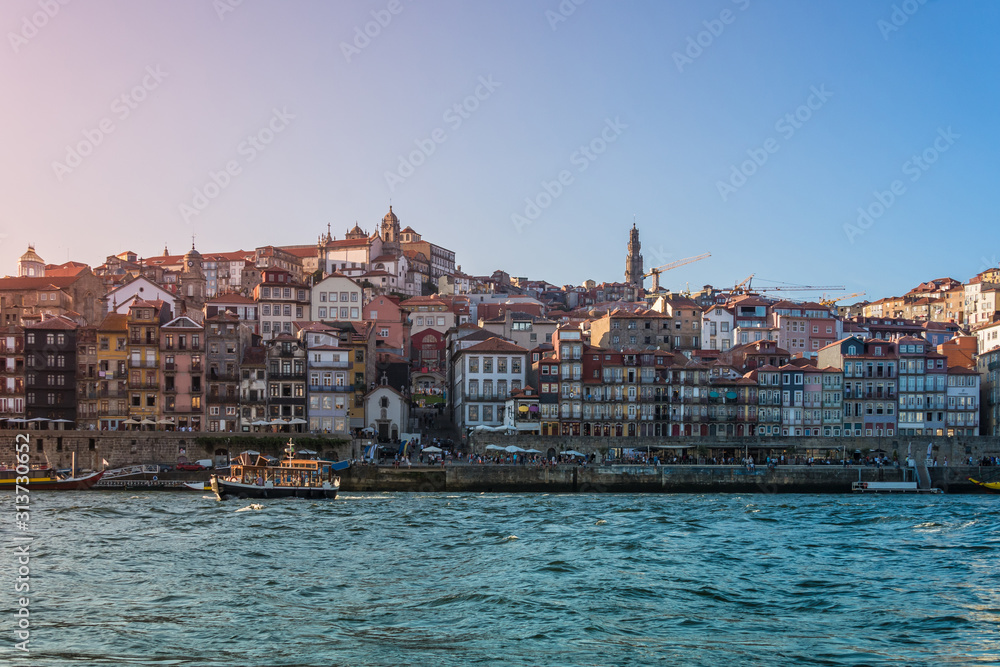 Porto, Portugal - Douro river with old boat and city skyline with colorful houses at summer sunset