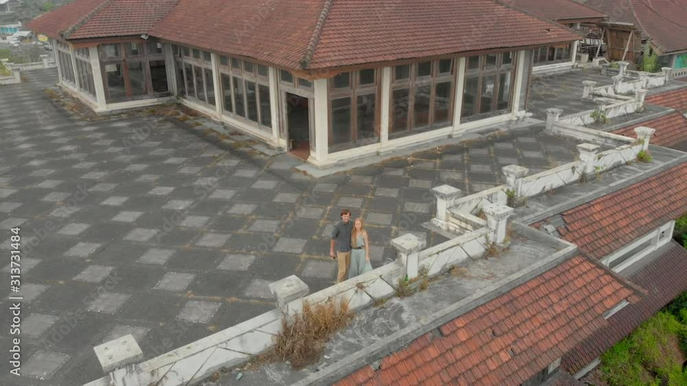 Aerial shot of a couple man and woman visiting the abandoned and mysterious hotel in Bedugul. Indonesia, Bali Island. Bali Travel Concept Aerial shot of a couple man and woman visiting the abandoned and mysterious hotel in Bedugul. Indonesia, Bali Island. Bali Travel Concept