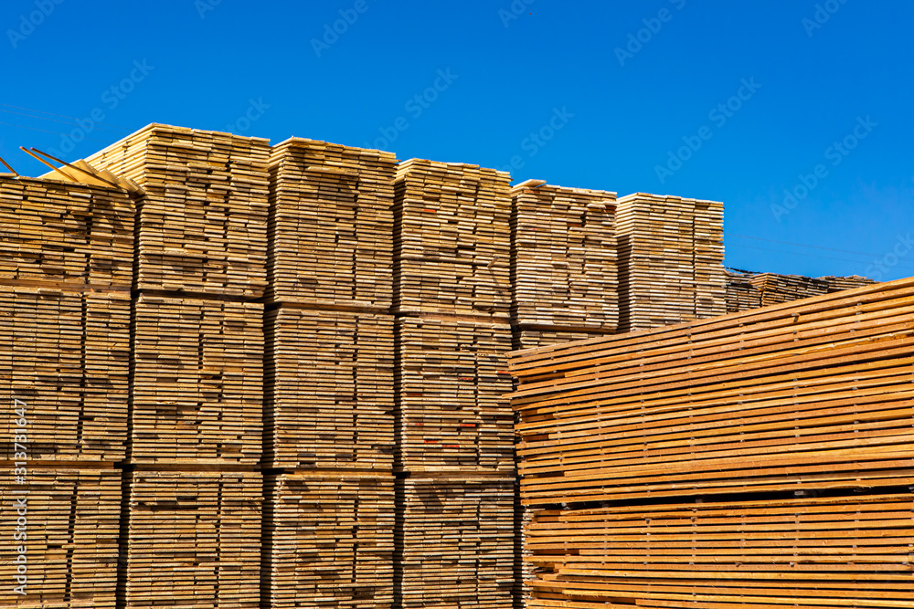 Large piles of sawn and processed wood boards are seen in a sawmill yard. Heavy industry in the Kootenays of British Columbia, Canada. With copy space