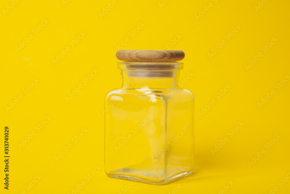 Closed empty glass jar on yellow background Closed empty glass jar on yellow background