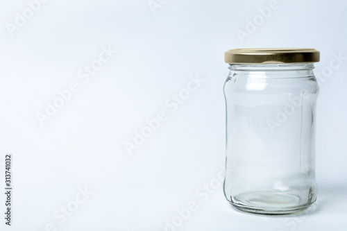 Closed empty glass jar on light background, space for text
