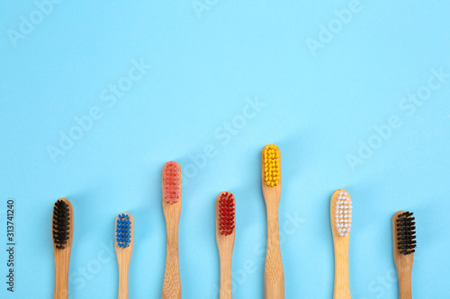 Toothbrushes made of bamboo on light blue background  flat lay. Space for text