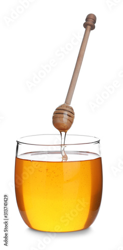 Honey dripping from wooden dipper into jar isolated on white