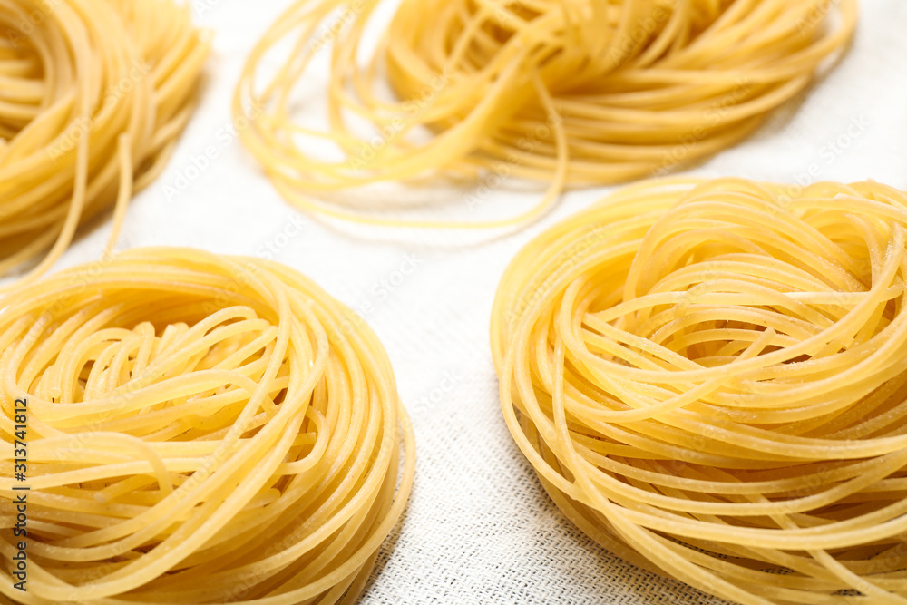 Capellini pasta on white tablecloth, closeup view Capellini pasta on white tablecloth, closeup view