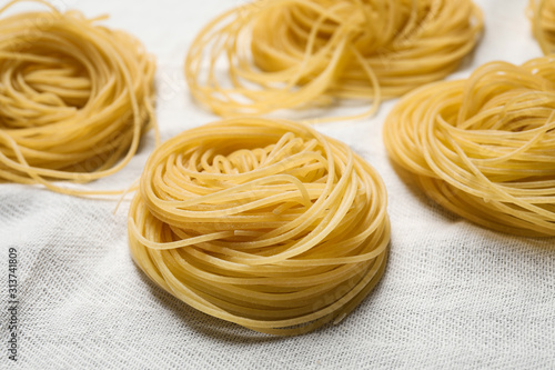 Capellini pasta on white tablecloth, closeup view