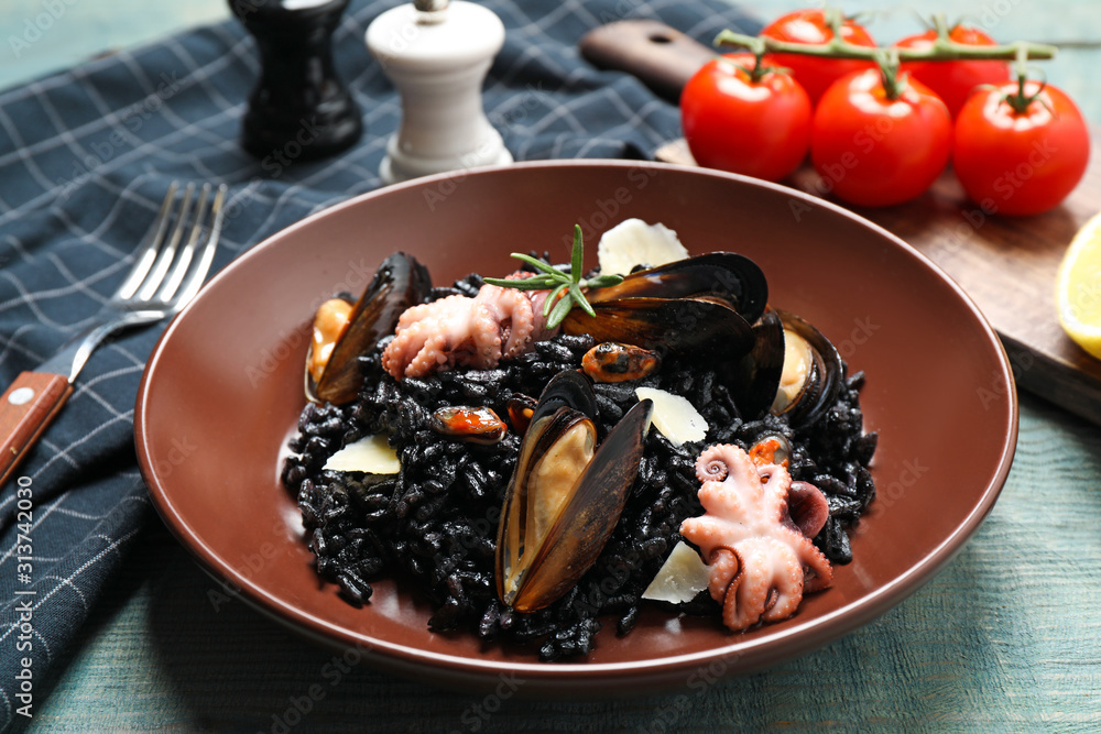 Delicious black risotto with seafood on blue wooden table, closeup Delicious black risotto with seafood on blue wooden table, closeup